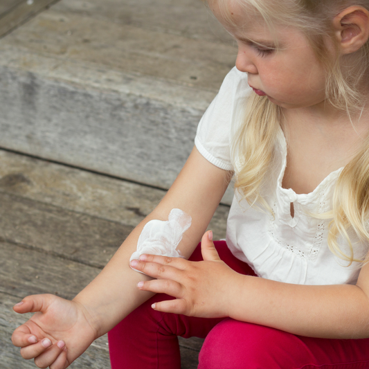 little girl applying cream to her eczema
