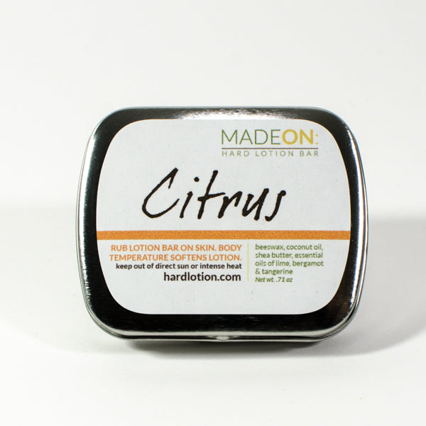 citrus scented lotion bar made with essential oils, in tin on white background
