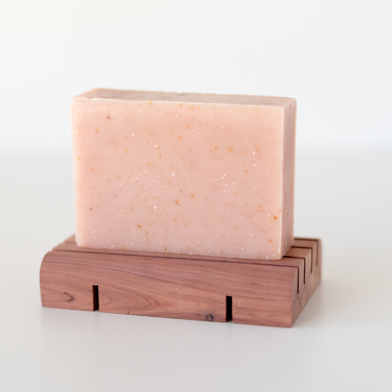 goat milk soap on a cedar wood soap deck against a white background