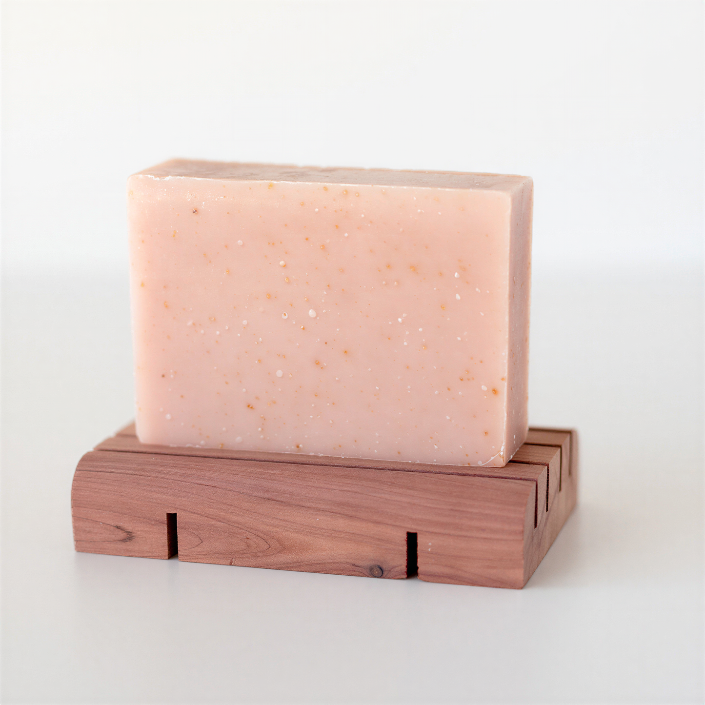 goat milk soap on a cedar wood soap deck against a white background