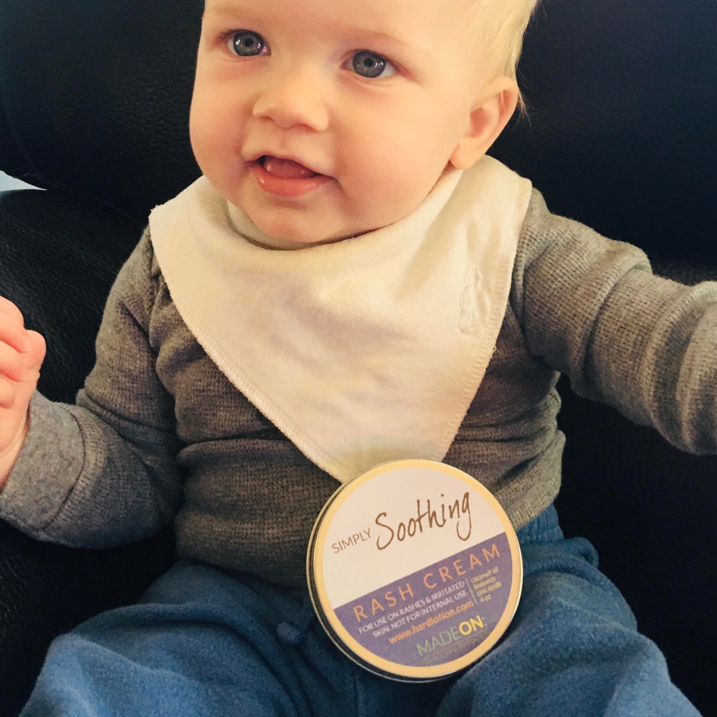 Baby with a tin of full size Simply Soothing Rash Cream made with safe edible ingredients (zinc oxide, beeswax and coconut oil)