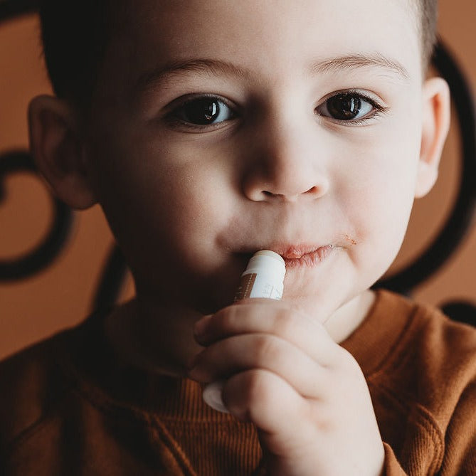 child applying lip balm to dry chapped lips