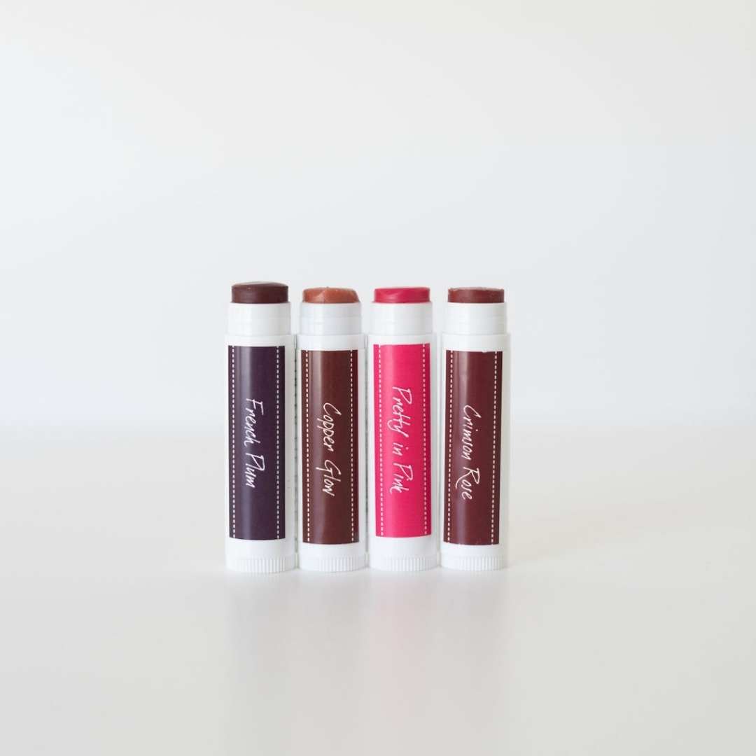 4 tinted lip balms on white background made with iron oxide and only 4 ingredients