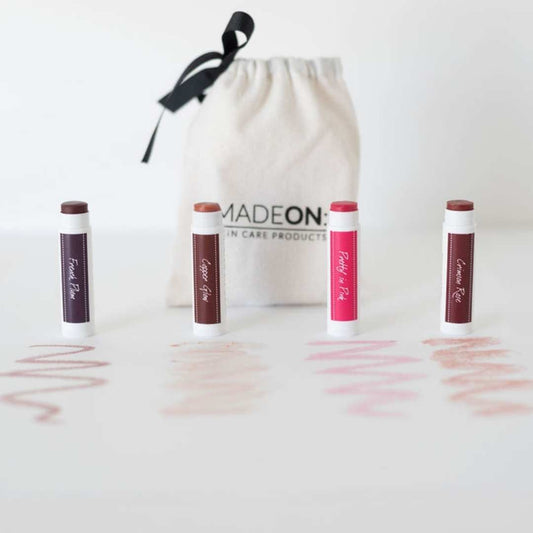 Pack of 4 MadeOn Skin Care tinted lip balm mineral lipstick with gift bag in 4 shades against white background