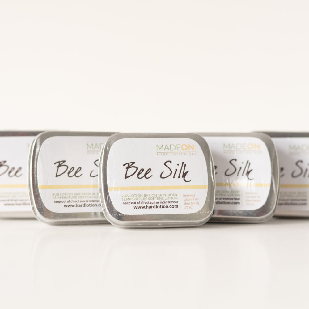 Beeswax based Beesilk lotion bars lined up in a row of 5 bars in tins.