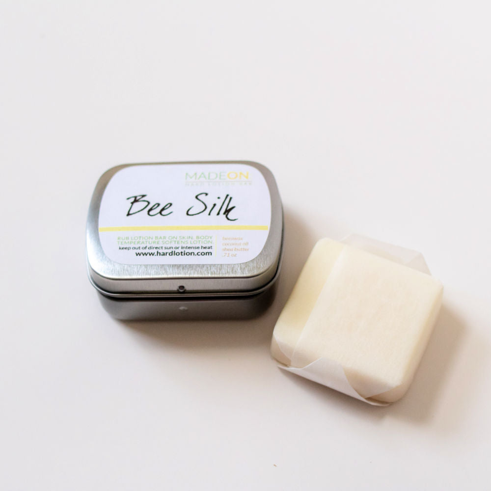 beeswax-based beesilk lotion bar next to a small tin with white background
