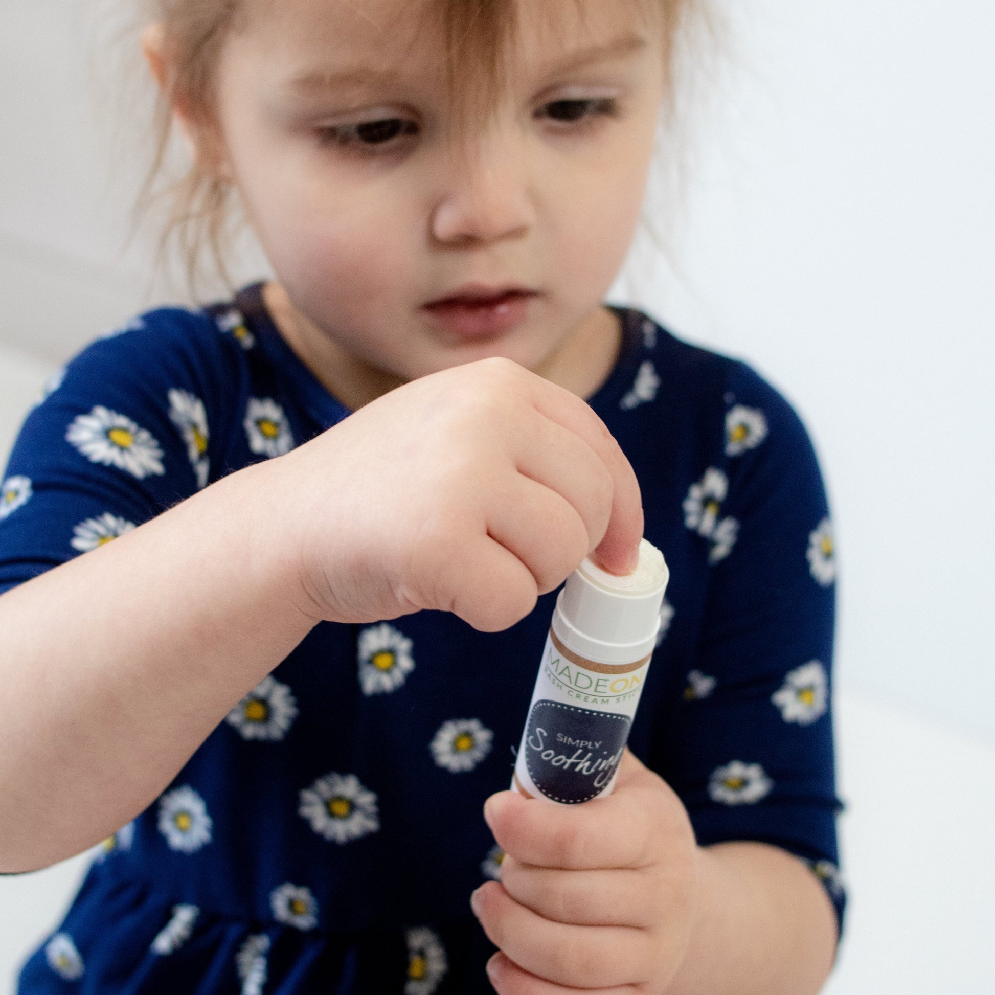 Little girl toddler scooping Simply Soothing Rash Cream out of the stick