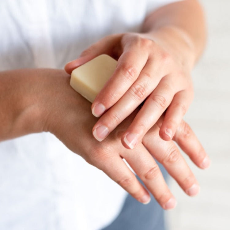 woman applying a beesilk hard lotion bar to her hands