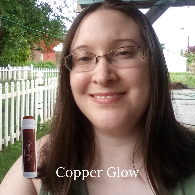 Woman showing Copper Glow tinted lip balm.  Iron oxide based mineral lipstick.