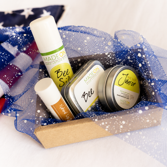 4 Beesilk Products for moisturizing lips, legs, hands, feet and more with American flag in background