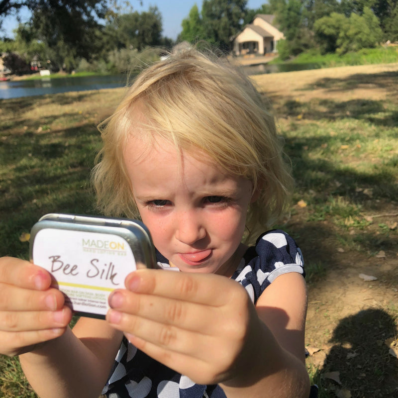 Toddler holding Beesilk Lotion Bar outdoors