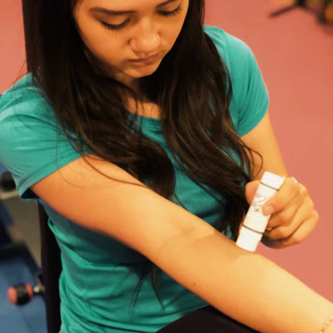 Teen girl applying BeeCool Muscle Balm to sore arm
