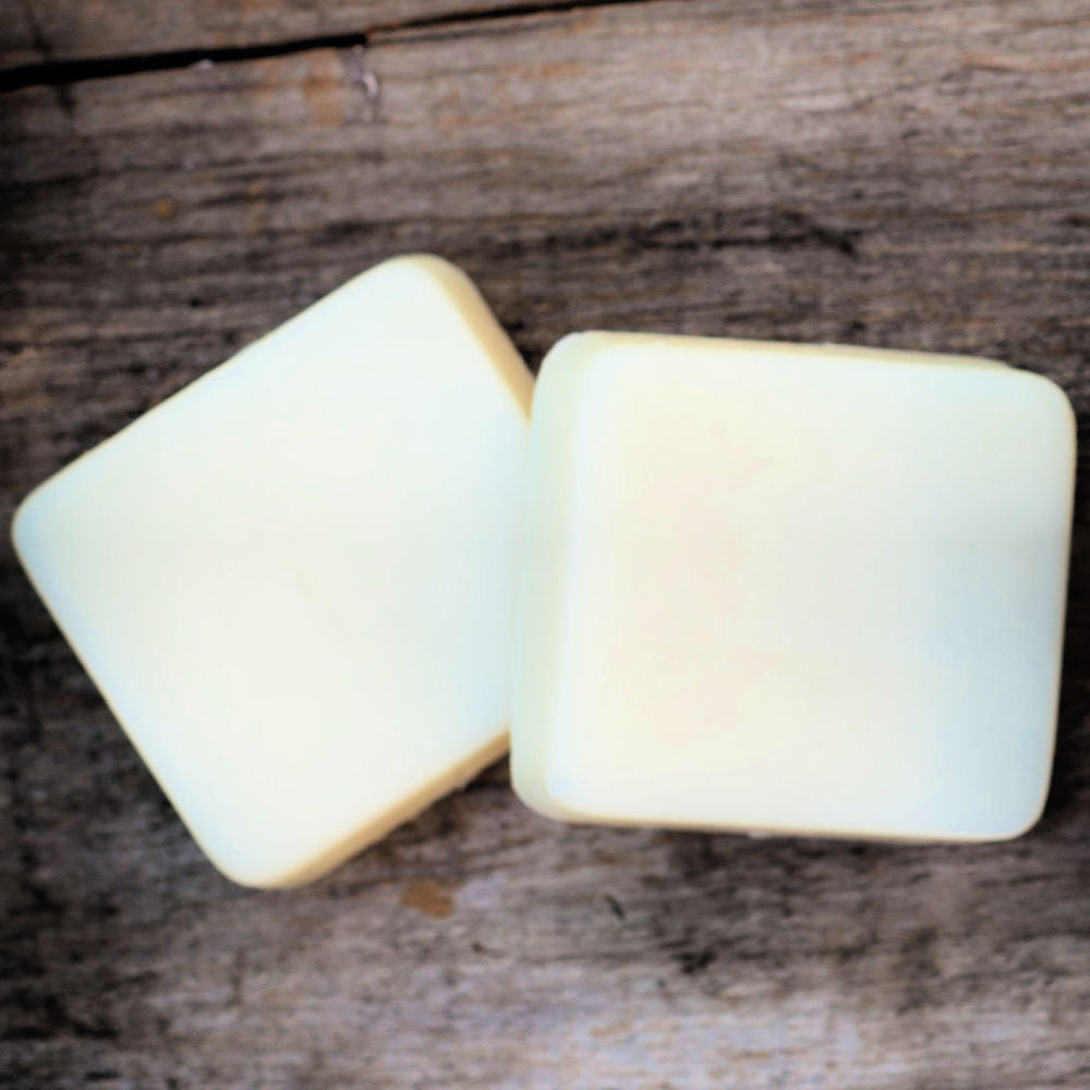 two plain lotion bars on wood plank background