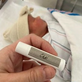 chai lip balm with newborn baby in the background