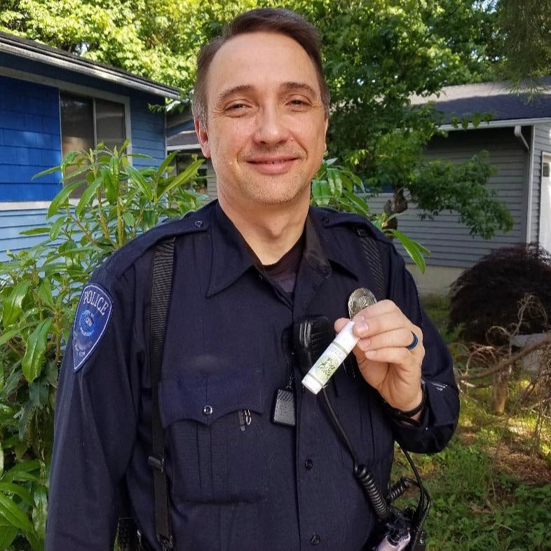 male police officer holding a beesilk lotion stick and smiling