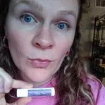 Woman holding a tinted lip balm to show the color