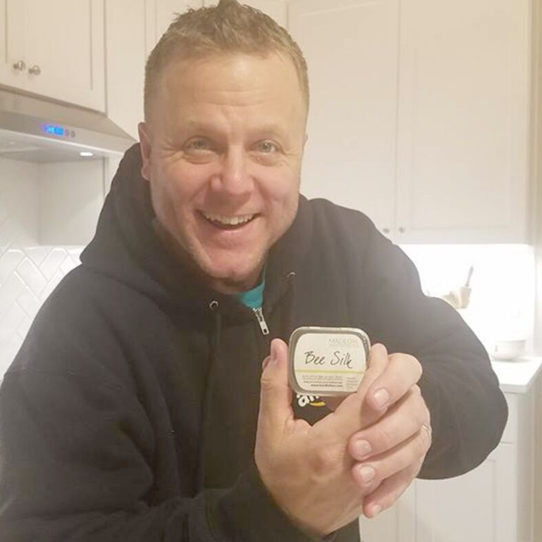 man holding a beesilk lotion bar in tin