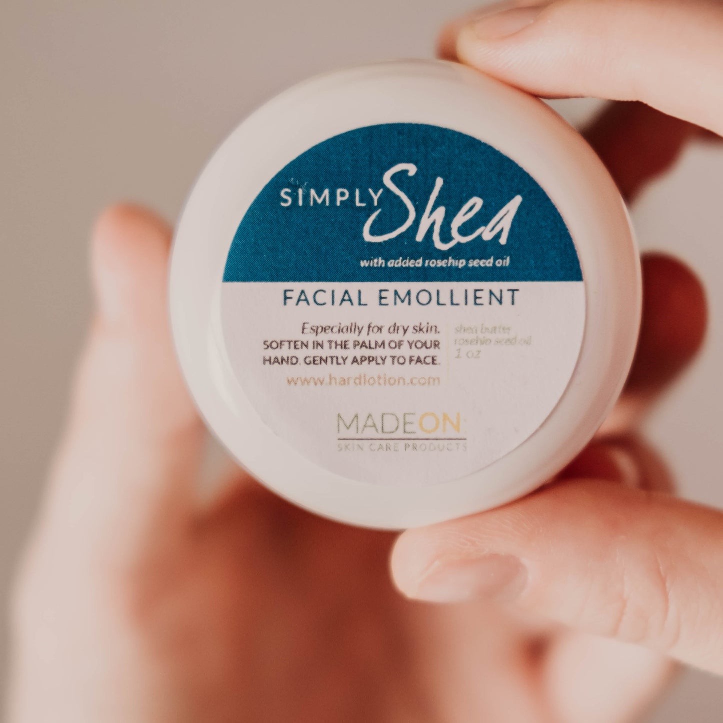 Hand holding a container of Simply Shea Facial Emollient to show its size