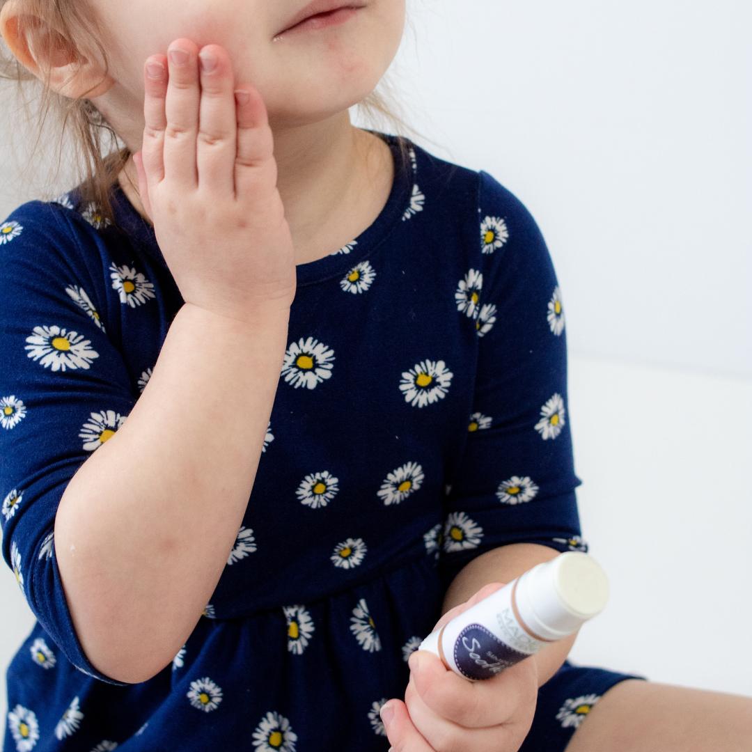 little girl applying rash cream to face