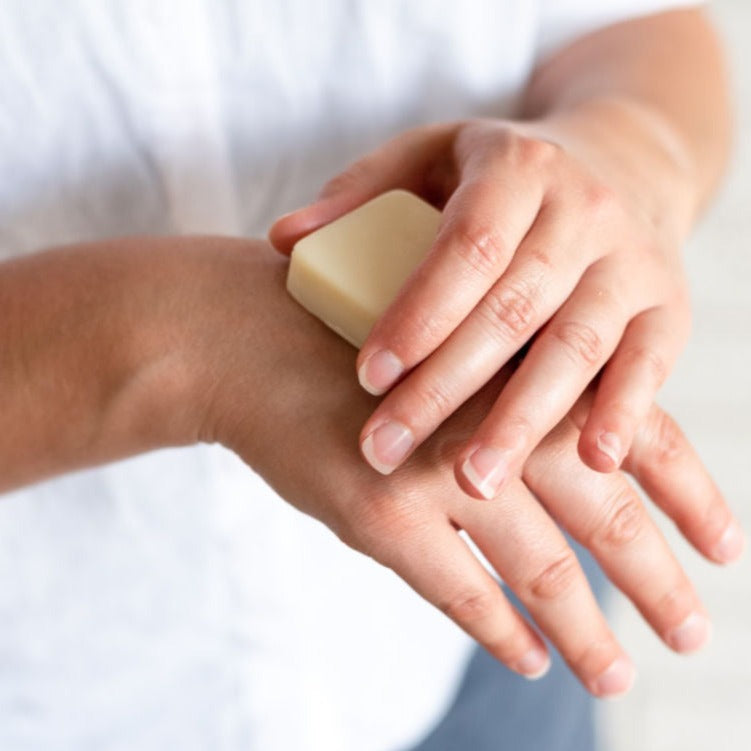 woman apply lotion bar to hands and dry skin